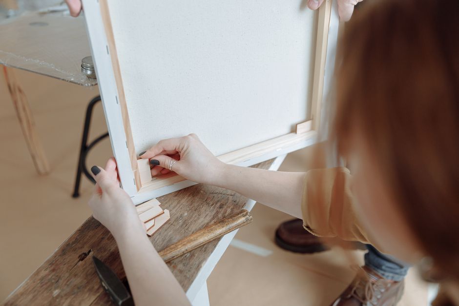 Persoon hangt canvas aan een muur. Persoon hangt canvas aan een muur.